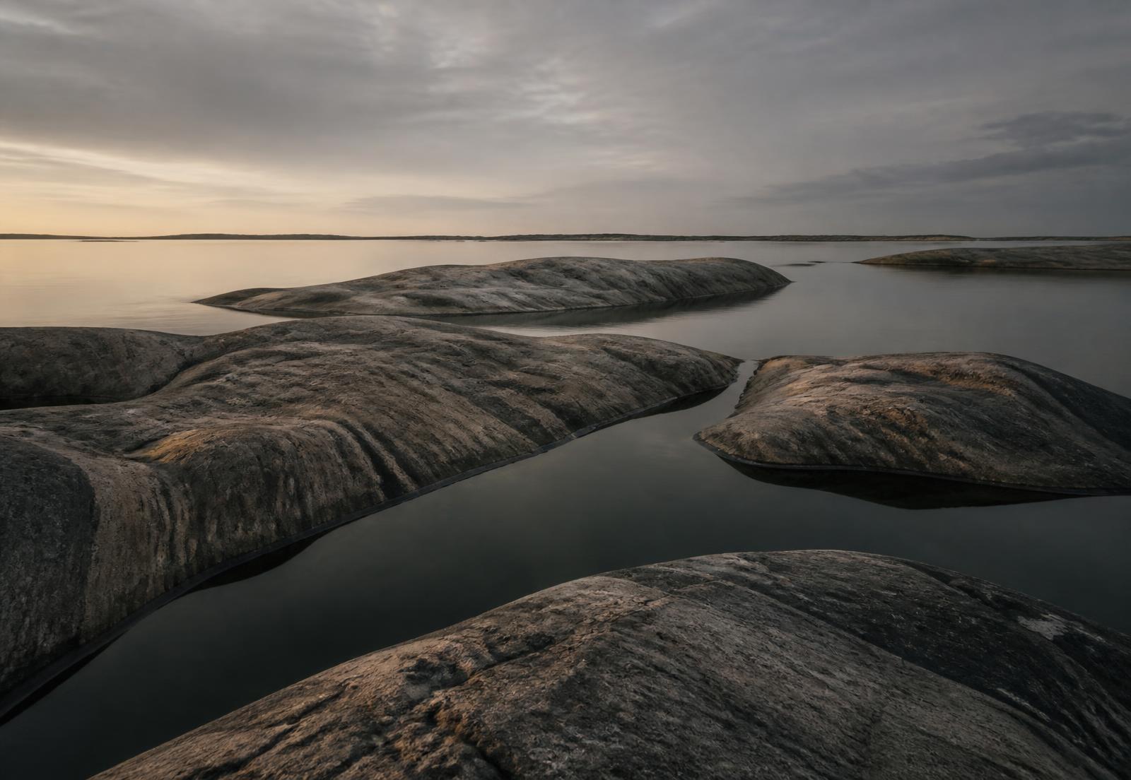 Wave-polished granite islands and still water in the Stockholm archipelago at dusk