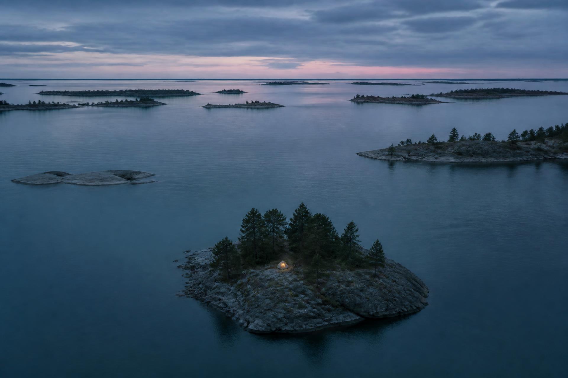A tiny tent on a rocky pine island in the Stockholm Archipelago at twilight